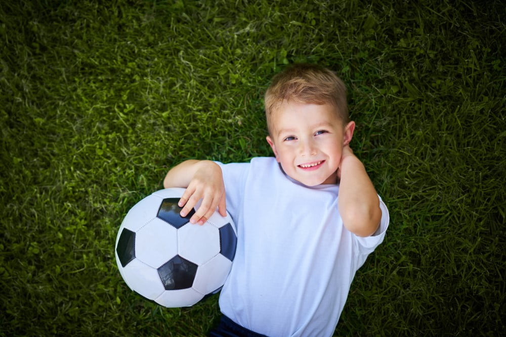 Dreng på græsset med en fodbold